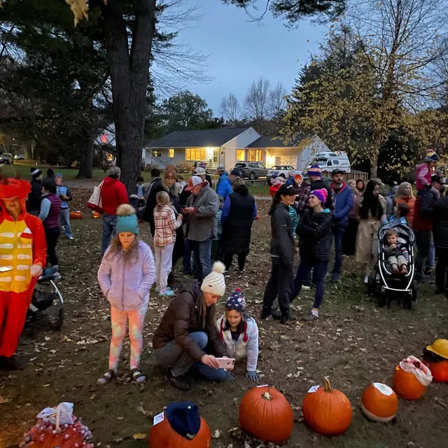 Neighbors gathered at dusk, checking out the line of pumpkins